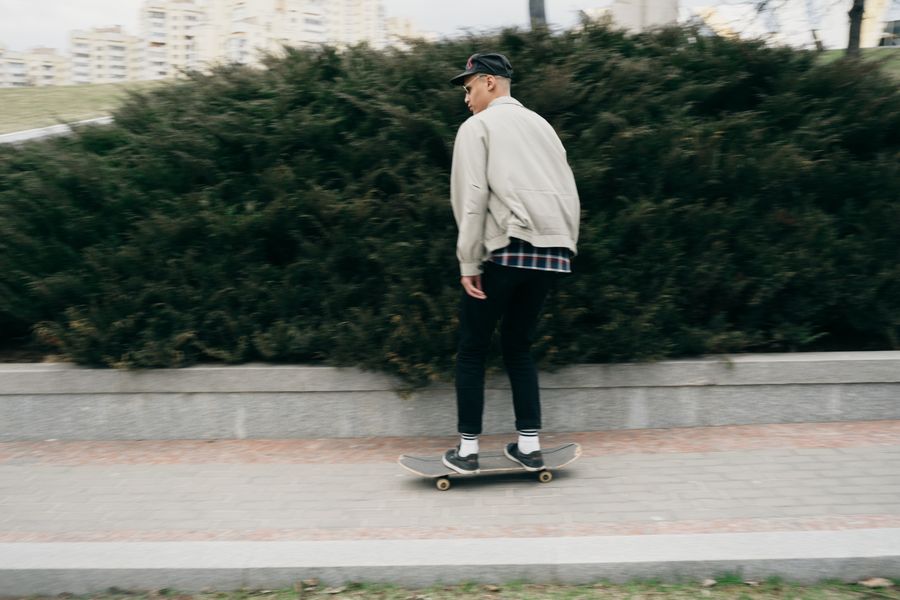Skateboarder rolling past a hedge, photo by Ivan S on Pexels