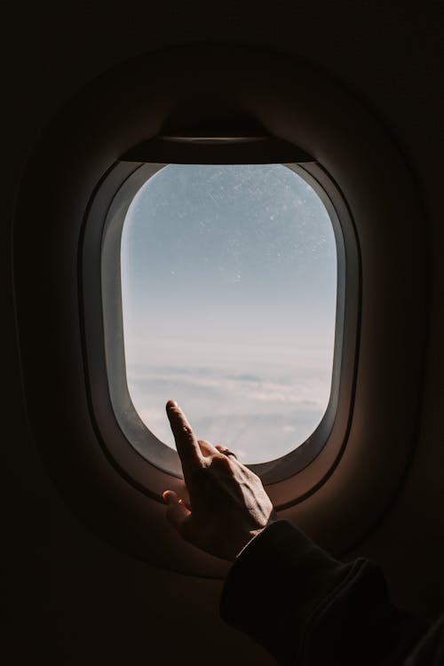 Person Pointing To The Sky From An Airplane Window