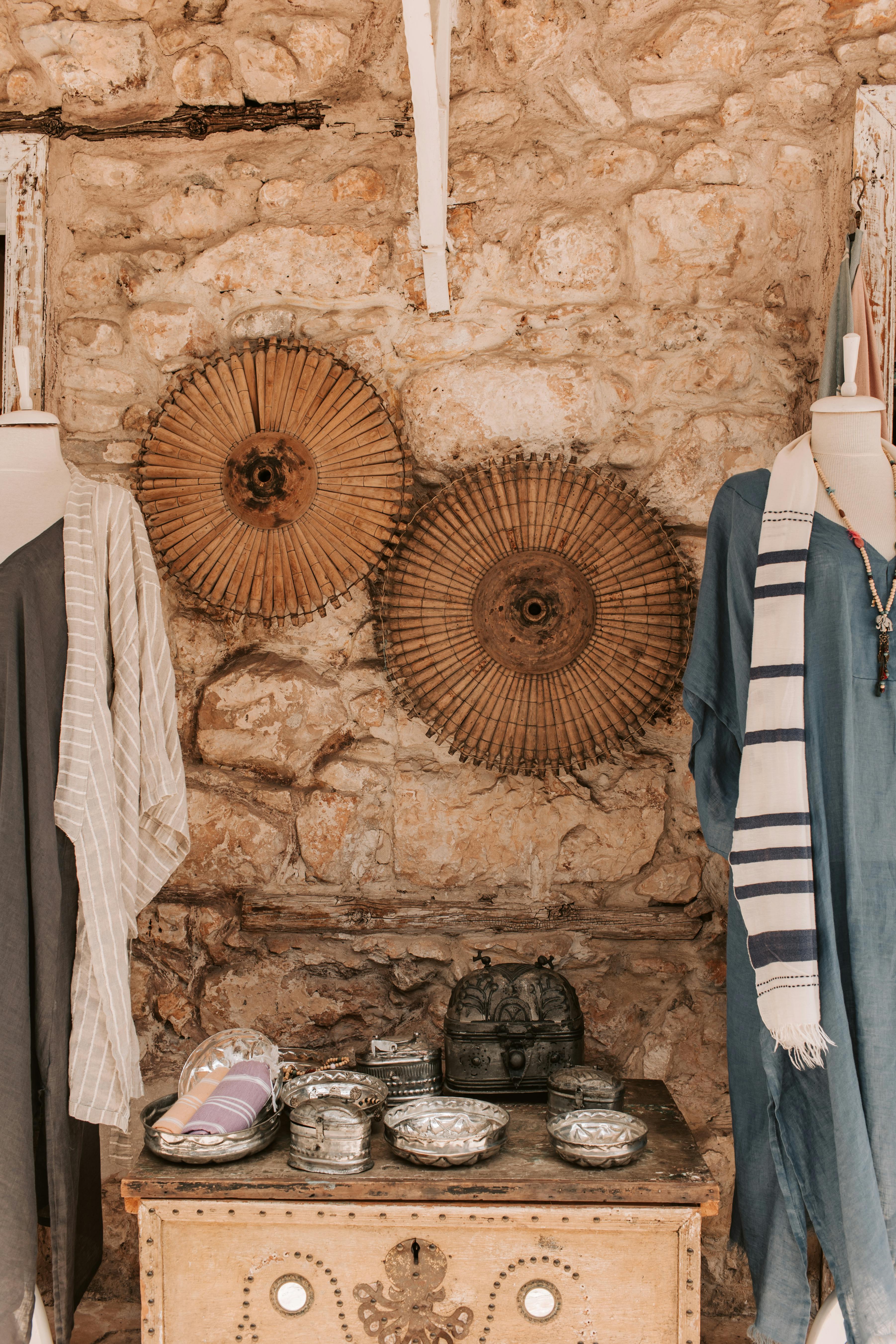 Rustic stone-wall shop showcasing vintage clothes and accessories on display mannequins.