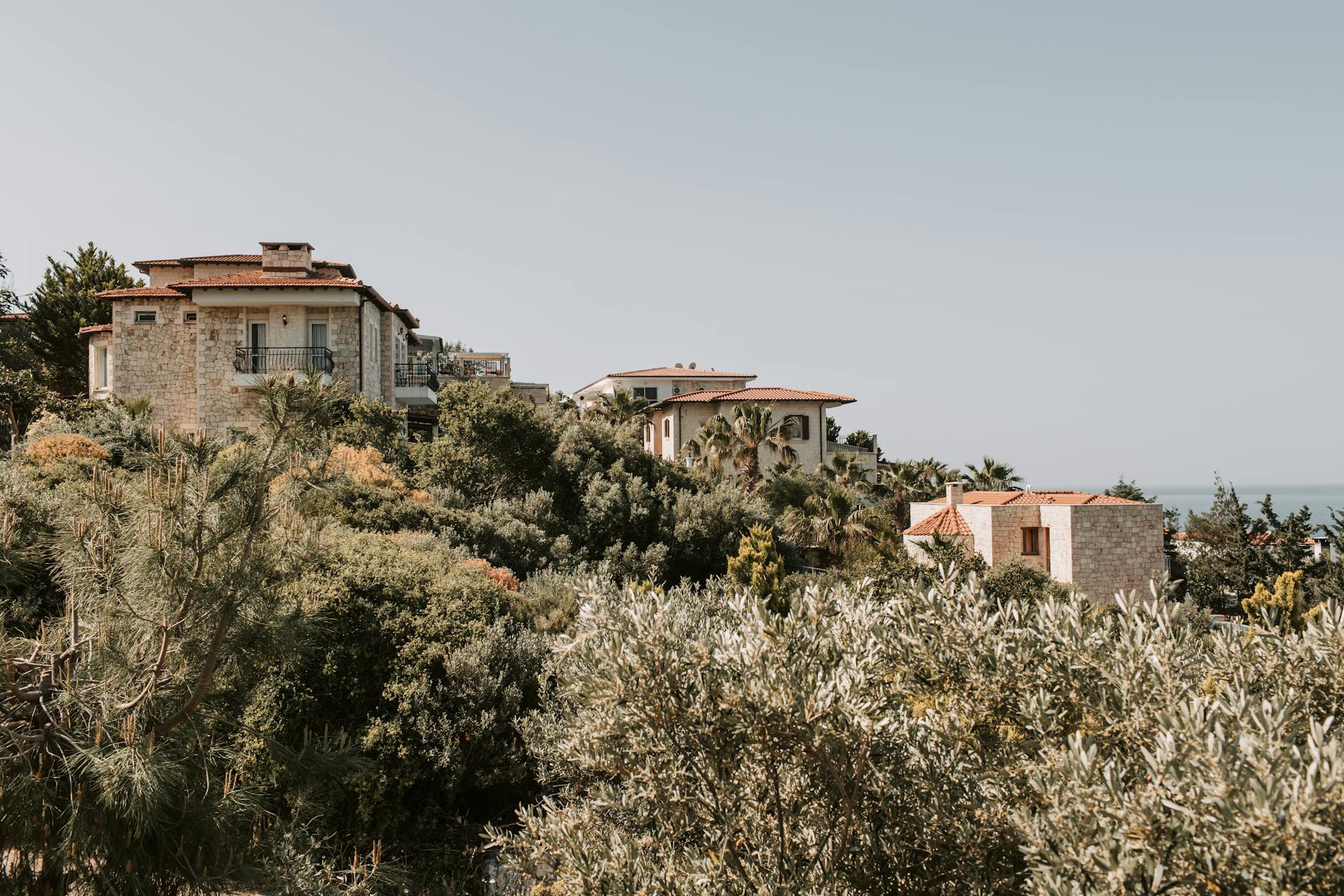 Charming villas nestled in Antalya with lush greenery and a sea view, perfect for a summer vacation.