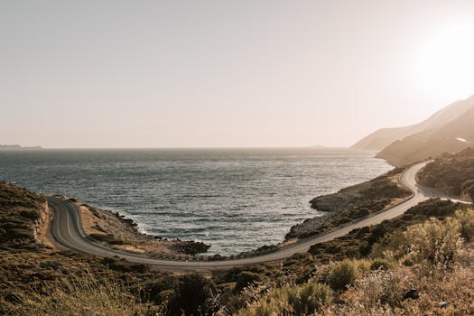 Aerial view of a winding coastal road in Antalya, Turkey, during a serene sunset.