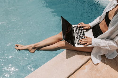 Free Woman Sitting on Poolside Using Laptop Stock Photo