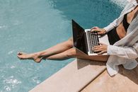Woman Sitting on Poolside Using Laptop