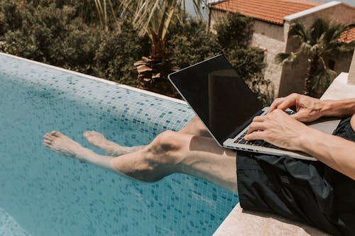 Crop Photo Of Man Using Black Laptop Computer on Swimming Pool