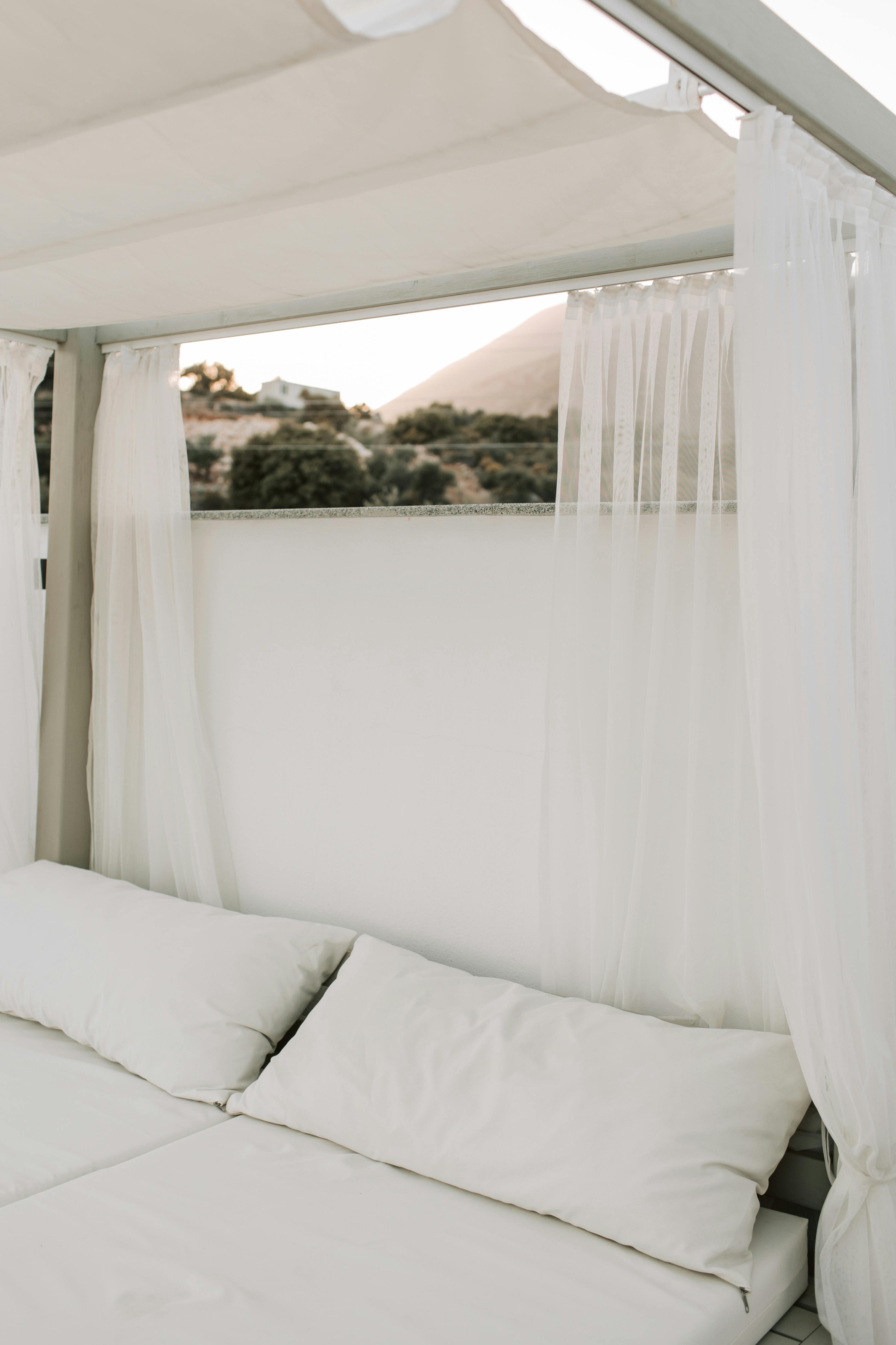 Elegant outdoor daybed surrounded by sheer curtains and mountain scenery.