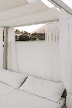 Elegant outdoor daybed surrounded by sheer curtains and mountain scenery.