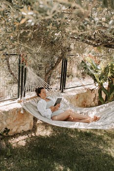 Woman Reading A Book While Lying On A Hammock with the Quote "The entrepreneur always searches for change, responds to it, and exploits it as an opportunity." written on it and have average color value #817359