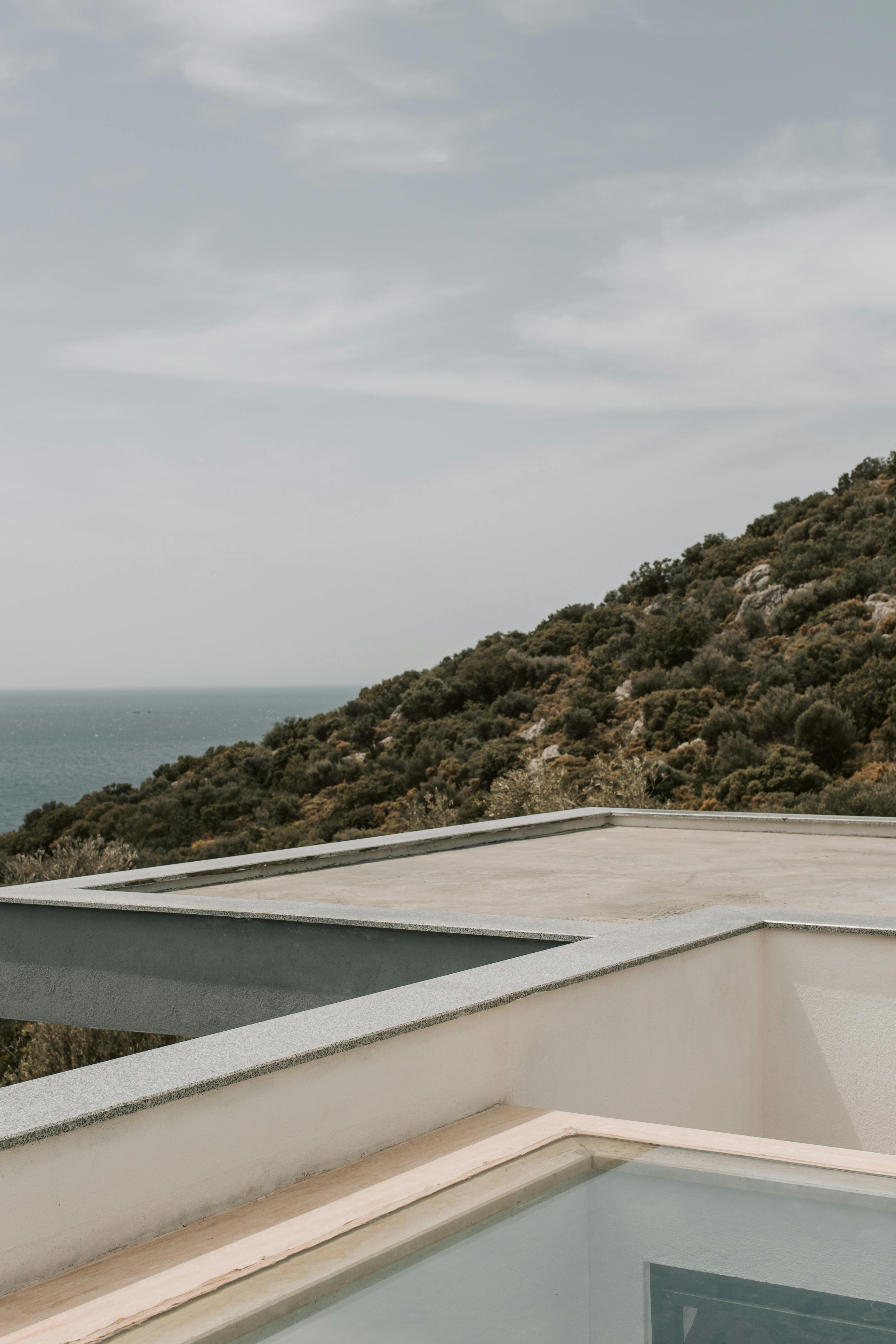 现代化的屋顶露台，俯瞰郁郁葱葱的山坡和晴朗的天空下的海洋