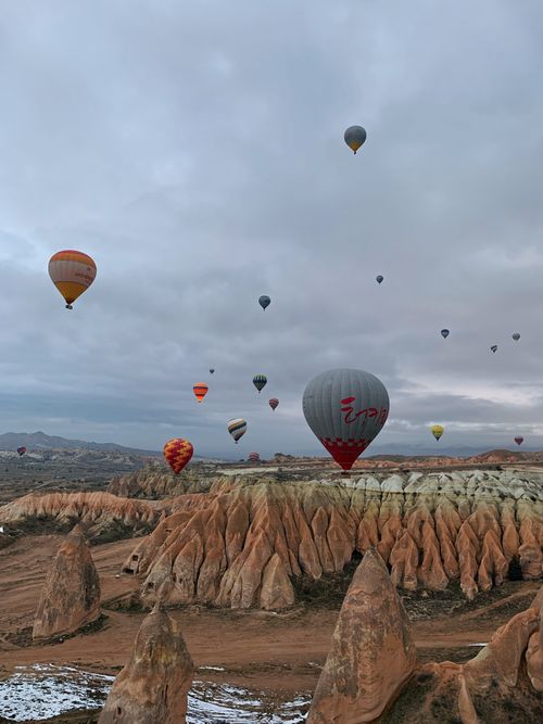 Free A beautiful view of hot air balloons soaring over the rocky formations of Cappadocia, Türkiye. Stock Photo