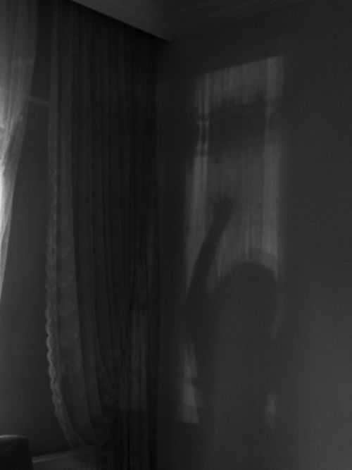 Free Ethereal silhouette of a woman cast on a curtain-covered wall, creating a mysterious ambiance. Stock Photo