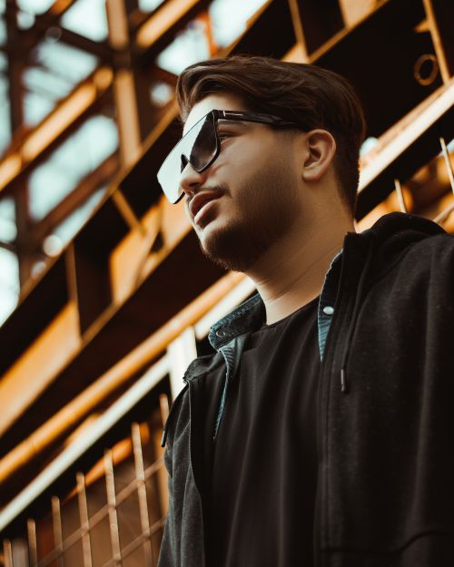 Free Portrait of a young man with sunglasses and facial hair in a modern urban environment. Stock Photo