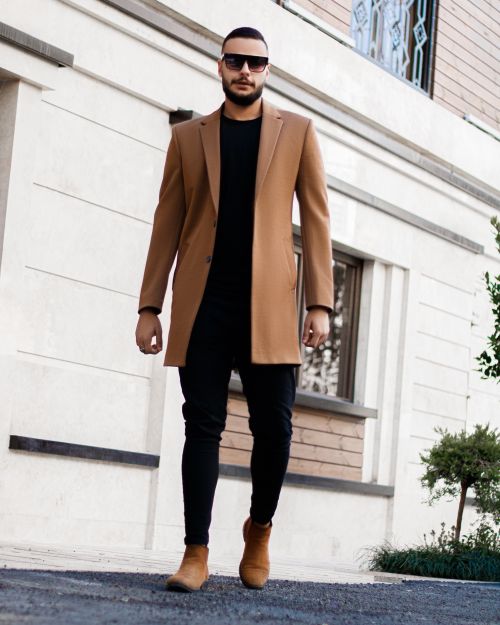 Free A fashionable adult man wearing a camel coat and sunglasses, walking outdoors. Stock Photo