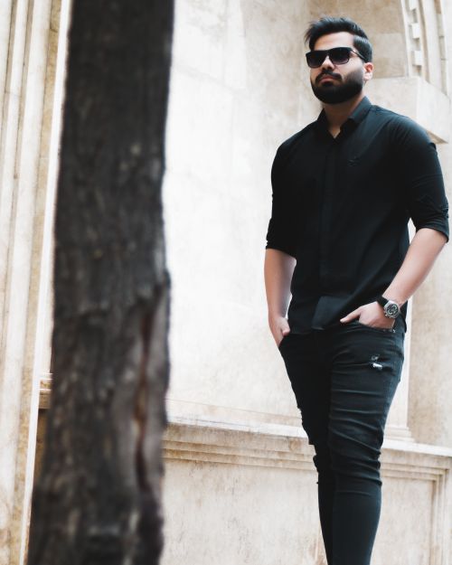 Free Fashionable man with beard and sunglasses posing outdoors in a modern urban setting. Stock Photo
