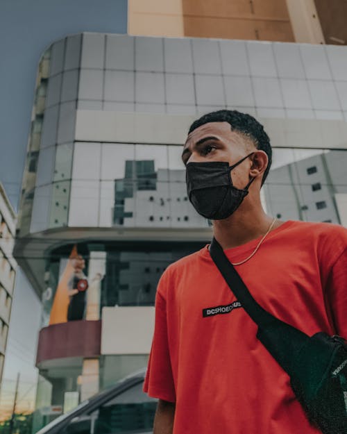 Young Man Wearing a Face Mask Standing on the Background of Modern Buildings in City