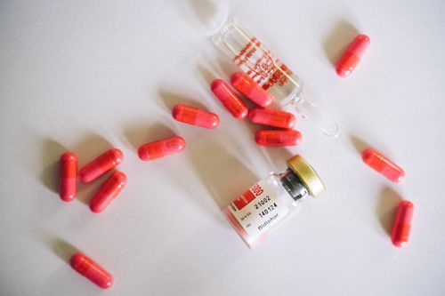 Free Red capsules and medical vials on a white background. Ideal for healthcare and pharmaceutical themes. Stock Photo