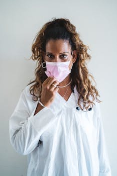 Portrait of a health professional in a white lab coat wearing a pink face mask for safety.