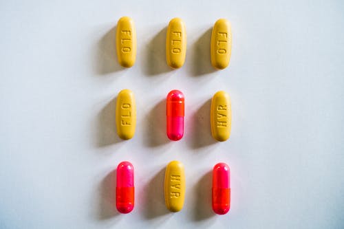 Gratis arkivbilde med gule piller, hvit bakgrunn, kapsler