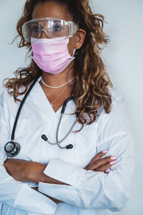 Free Portrait of a female doctor with a stethoscope, face mask, and protective goggles. Stock Photo