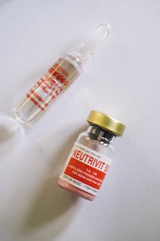 Flat lay of healthcare ampule and medicine bottle on a white background.