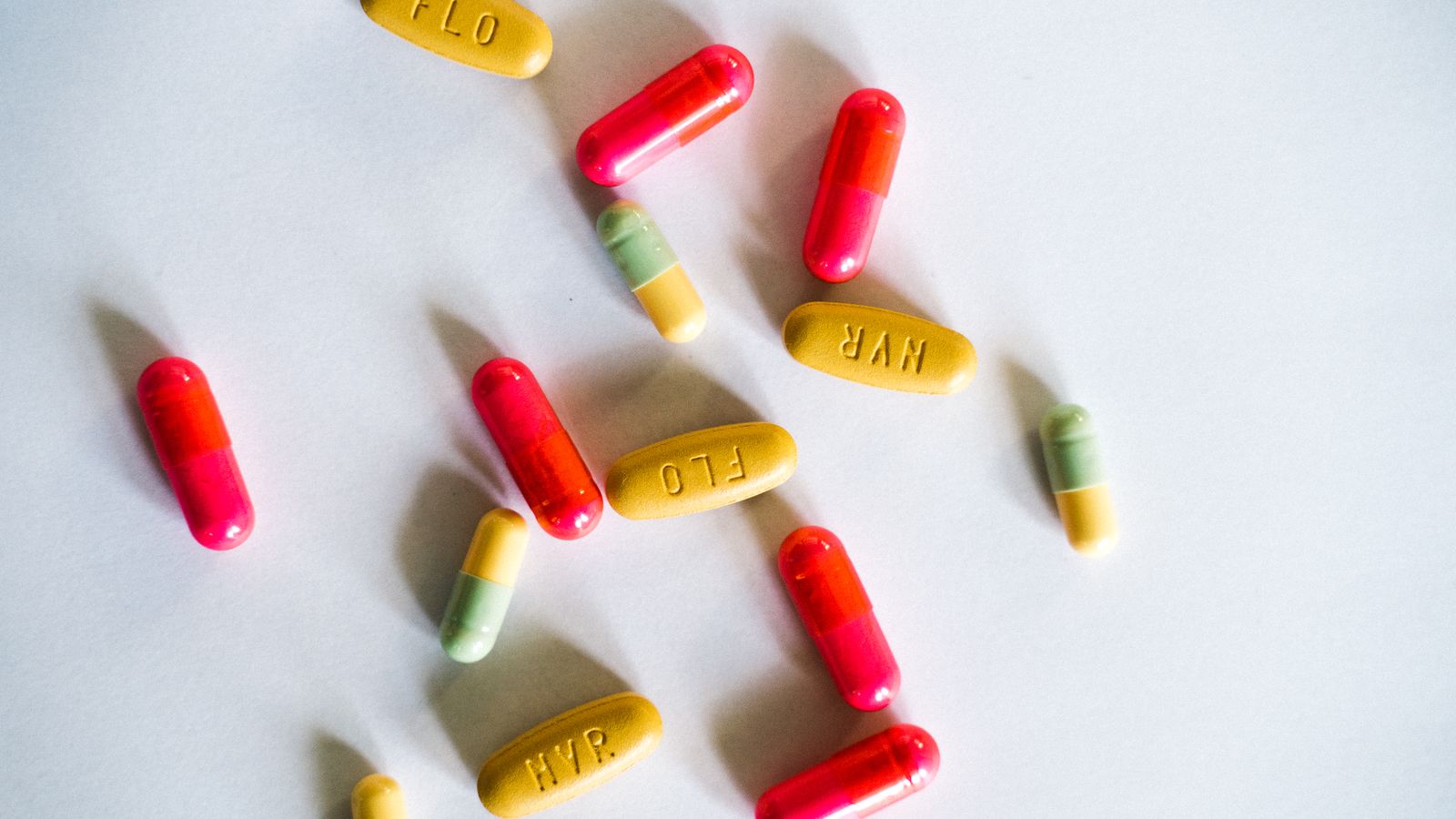 A vibrant assortment of colorful capsules and pills scattered on a white surface.