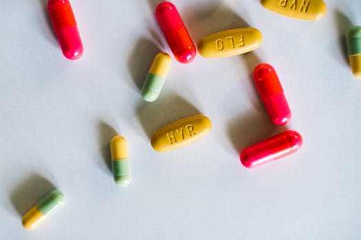 Close-up of various colored pills and capsules scattered on a white background.
