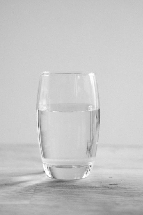 Free A simple, clear glass of water on a white surface, embodying a minimalist aesthetic. Stock Photo