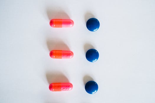 Vibrant pink and blue medication capsules arranged on a clean white surface for healthcare concept.