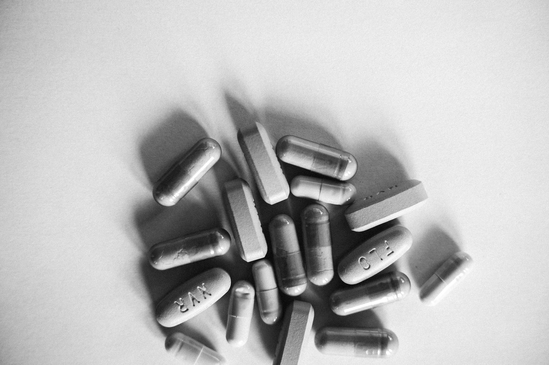 fenbendazole dosing for colon cancer — Grayscale image showing various capsules and tablets on a white surface.