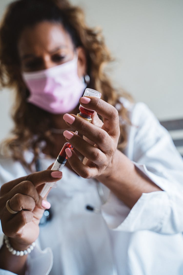 A Woman Holding A Vial And Syringe