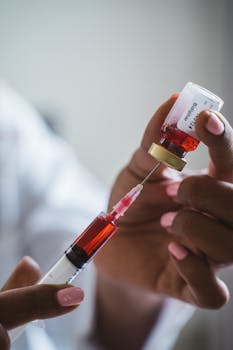 Close-up of hands holding a syringe and vial, depicting medical procedures.