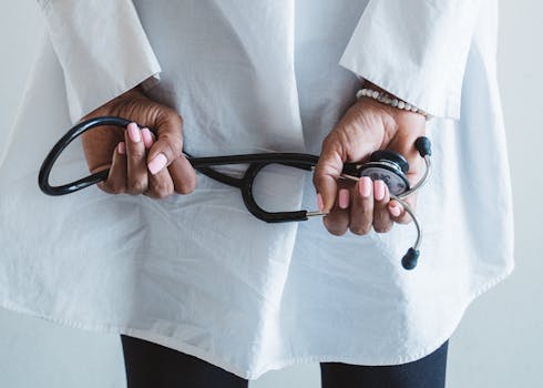 A medical professional holding a stethoscope in a clinical setting.