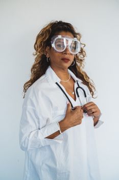 Female doctor wearing goggles and stethoscope, exuding confidence in medical attire.