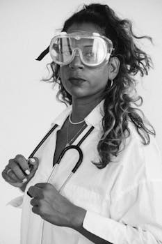 Black and white portrait of a female doctor with protective eyewear and stethoscope.