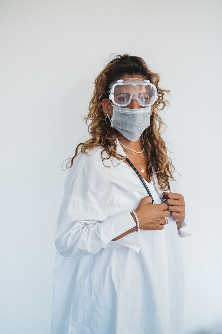 Woman In Medical Gown Wearing Safety Glasses And Face Mask