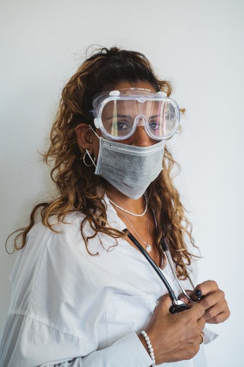 Free Portrait of a healthcare worker wearing protective gear, including goggles and a face mask. Stock Photo