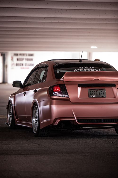 Free Close-up of a modified Subaru sports car parked indoors with custom wheels and spoiler. Stock Photo