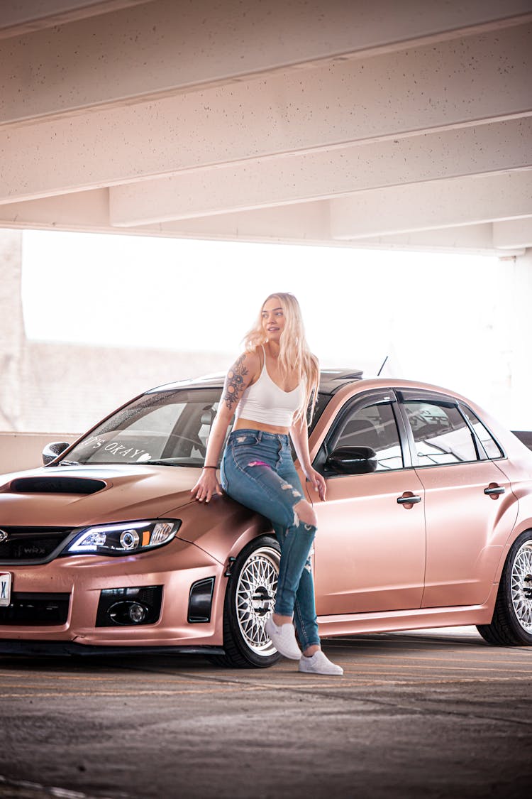 A Woman In White Tank Top Sitting Near The Car Hood