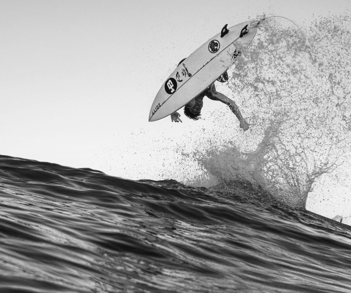 Black-and-white shot of a surfer flying off the top of a wave on the Miyazaki coast