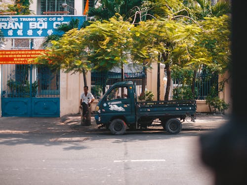 Man Standing by the Truck Parked on the Street under the Palm Trees