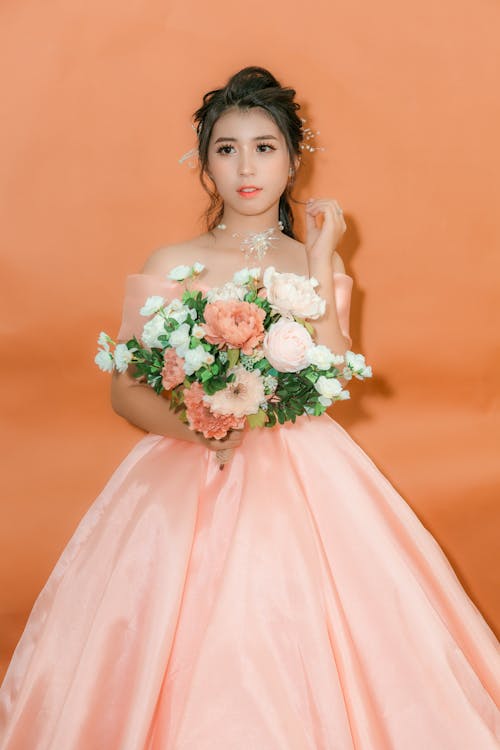 A Woman in Pink Wedding Dress Holding a Bouquet of Flowers