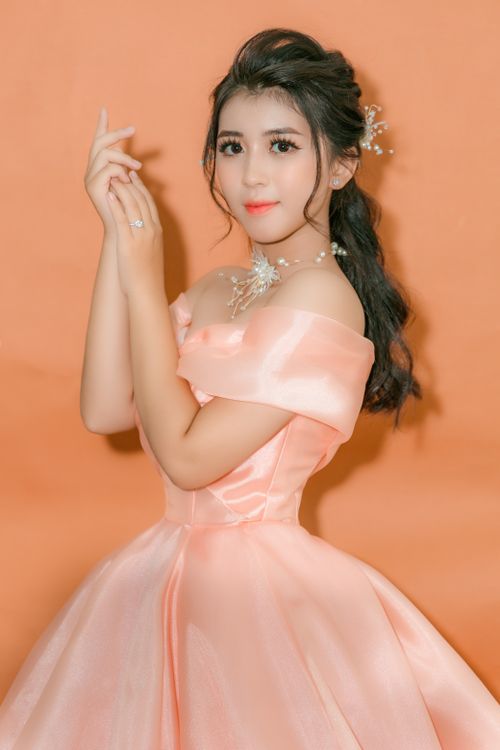 Free Studio shot of an elegant woman in a pink gown against an orange background. Stock Photo