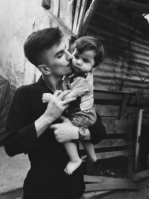 Grayscale Photo of Man Carrying a Child