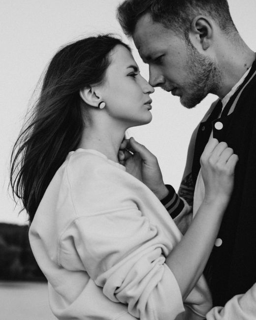 Black and white of loving couple standing close together while hugging and looking at each other on street