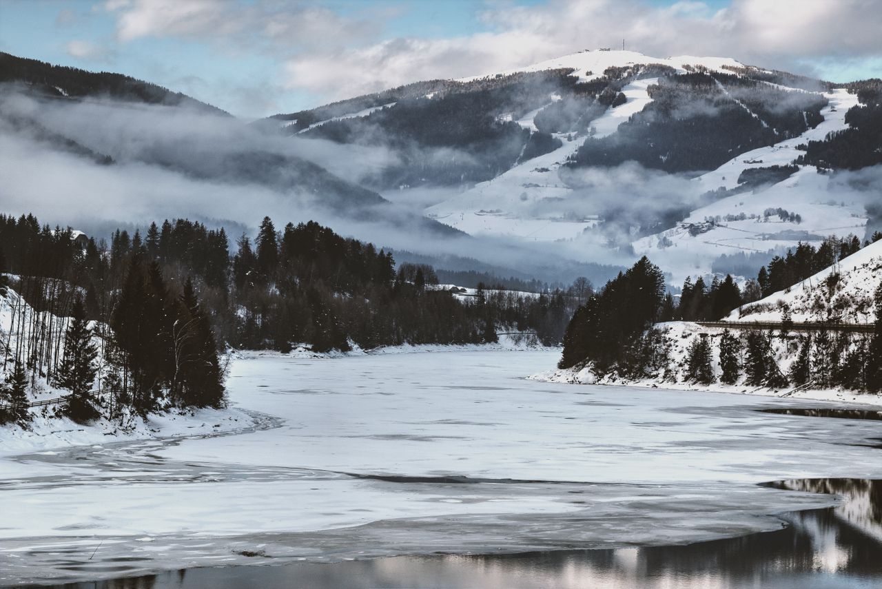 captivating winter scene of a frozen lake surrounded by snowy mountain