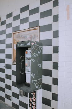 Retro payphone with artistic design on checkered wall in Austin, Texas.