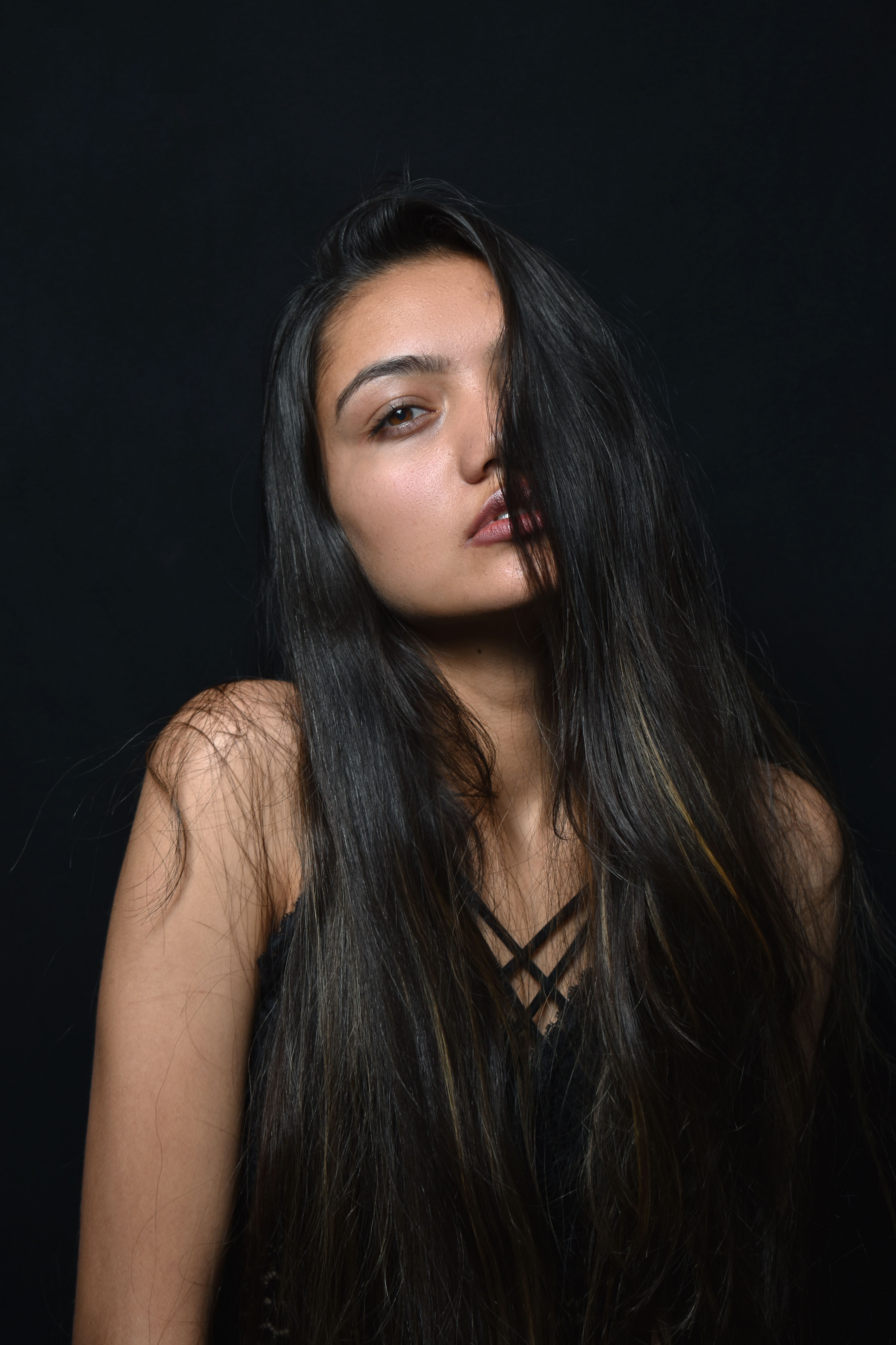 Striking portrait of a woman with long dark hair against a soft black background.