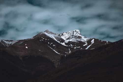 Free Breathtaking view of high rocky mountain slope covered with white snow under cloudy dark sky Stock Photo