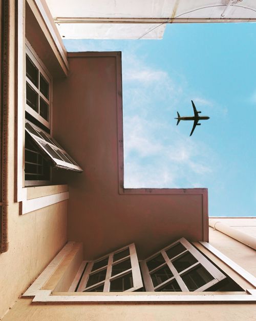 Free View of an airplane flying over urban architecture with open windows and blue sky. Stock Photo