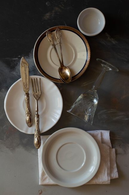 Flat lay of a sophisticated table setting featuring vintage silverware and fine porcelain plates.
