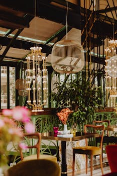 Stylish restaurant interior design featuring modern chandeliers, vibrant plants, and elegant table settings.